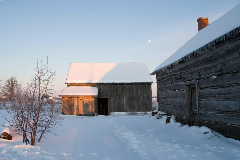 an old barn in the middle of a snowy field