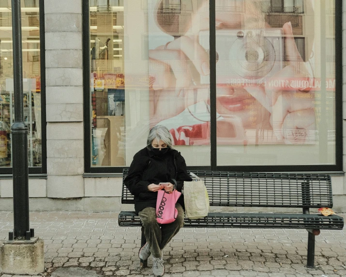 an elderly woman sitting on a bench in front of a store