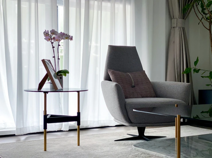 a living room with white curtains, chairs and a coffee table