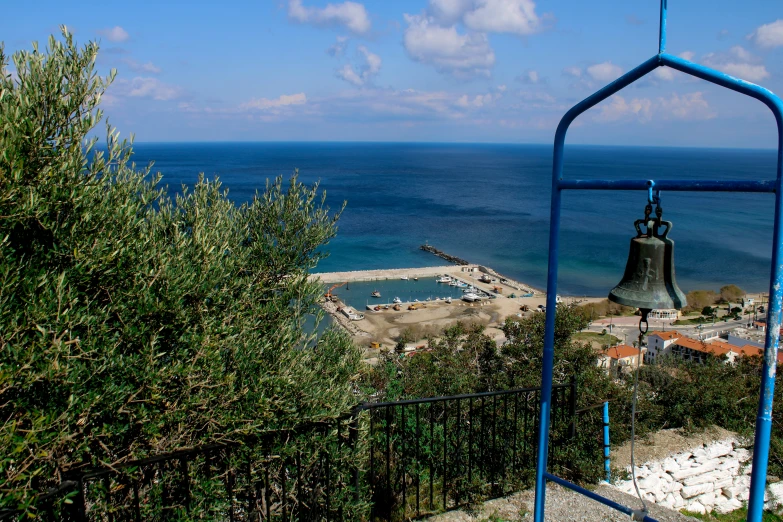 a bell is on a pole in front of the ocean