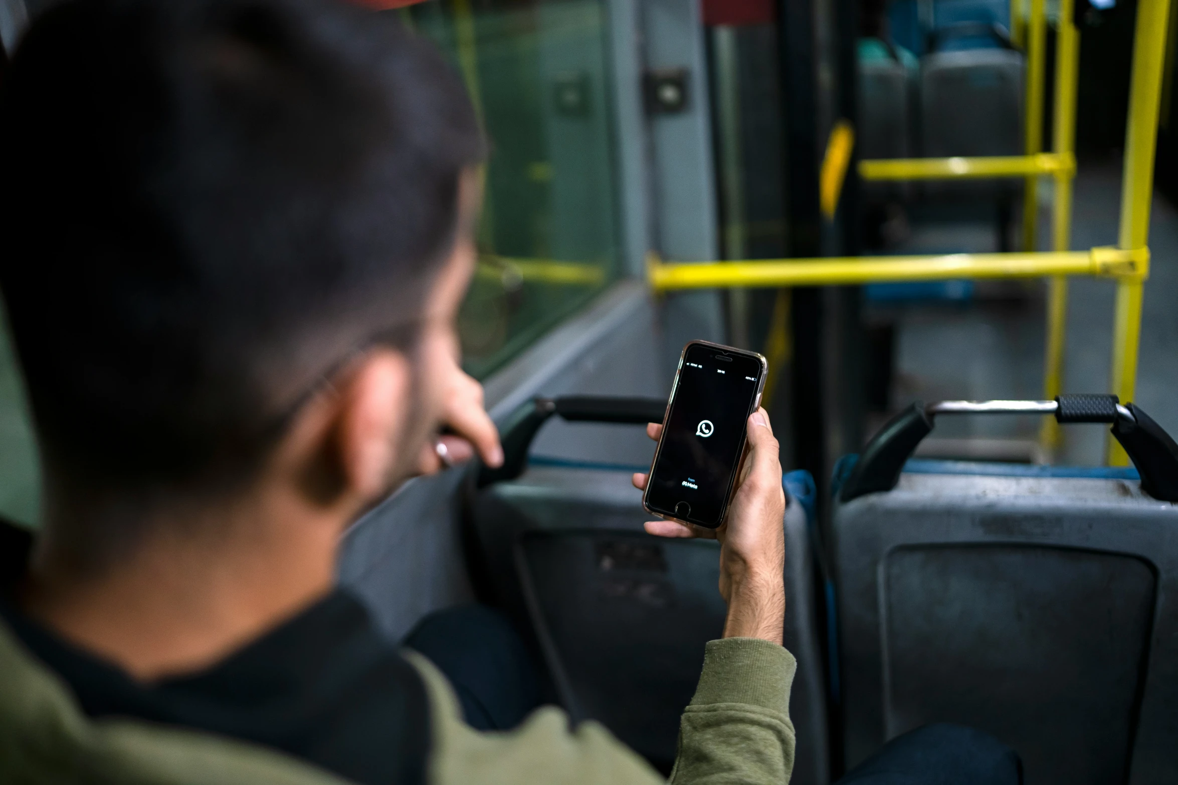 a man uses his phone to take a picture of his surroundings on the bus