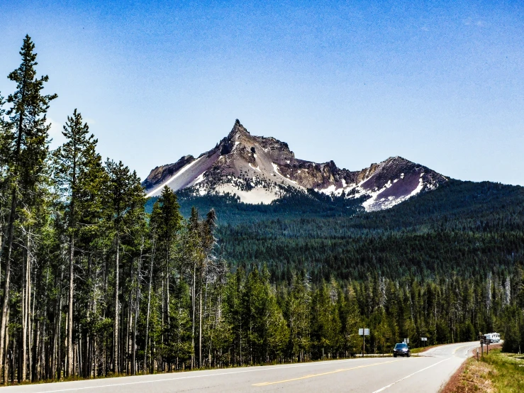 mountains rise above the trees on a highway