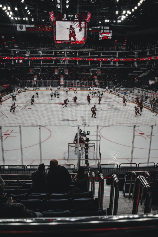 people watch as hockey game is played in an empty stadium