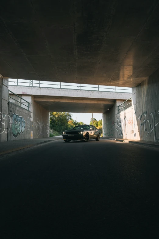 a truck going underneath a large bridge with graffiti