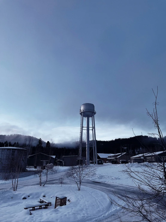 a snowy day in the countryside with a water tower