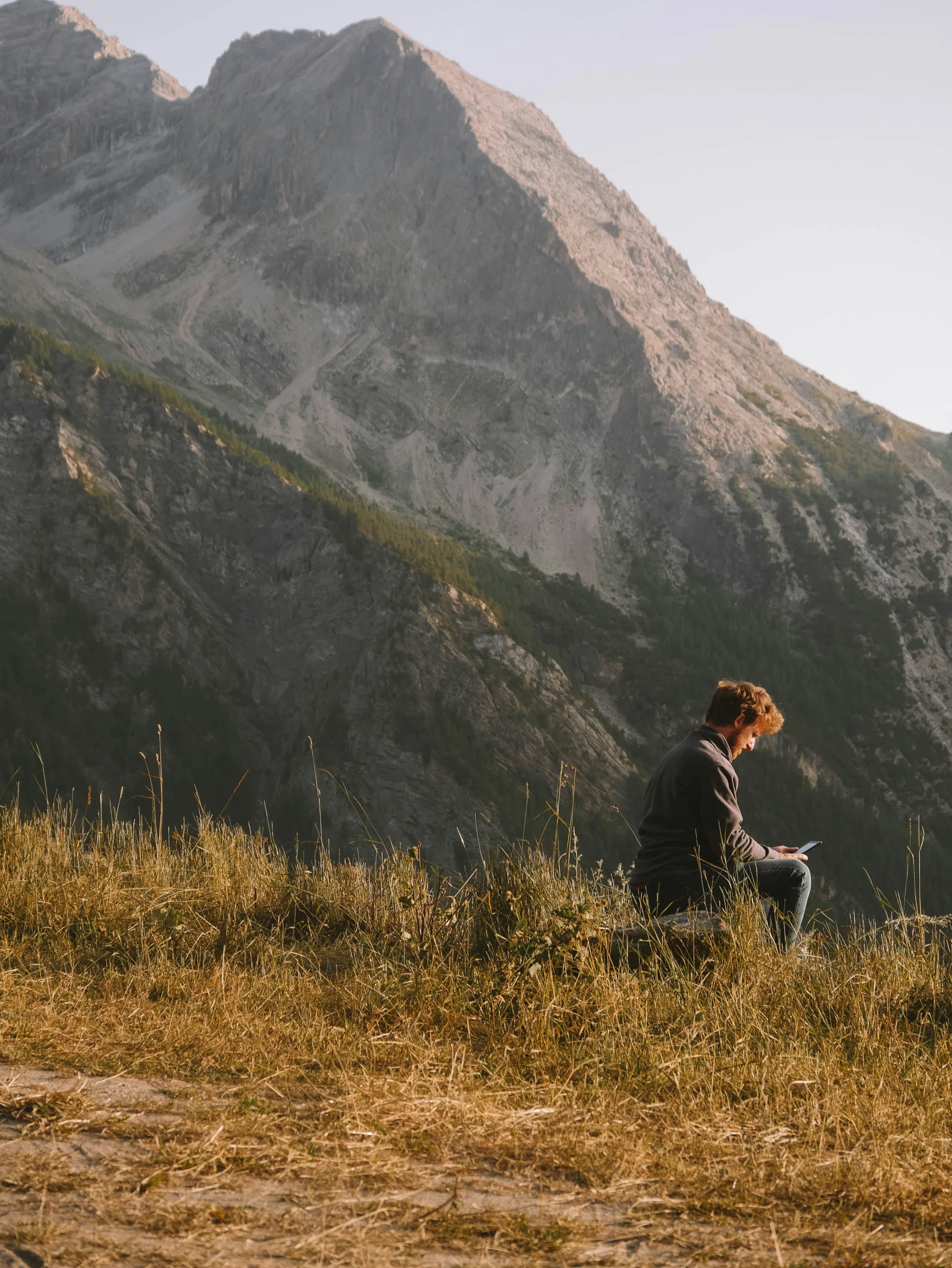 the young man is sitting on the top of a hill