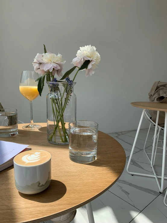 white flowers on a table next to some glasses with yellow liquid