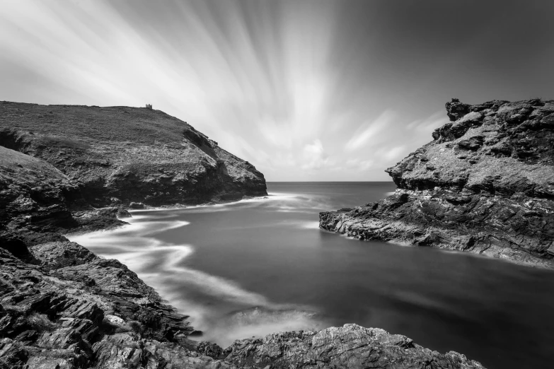 a black and white picture of water between two rocky hills