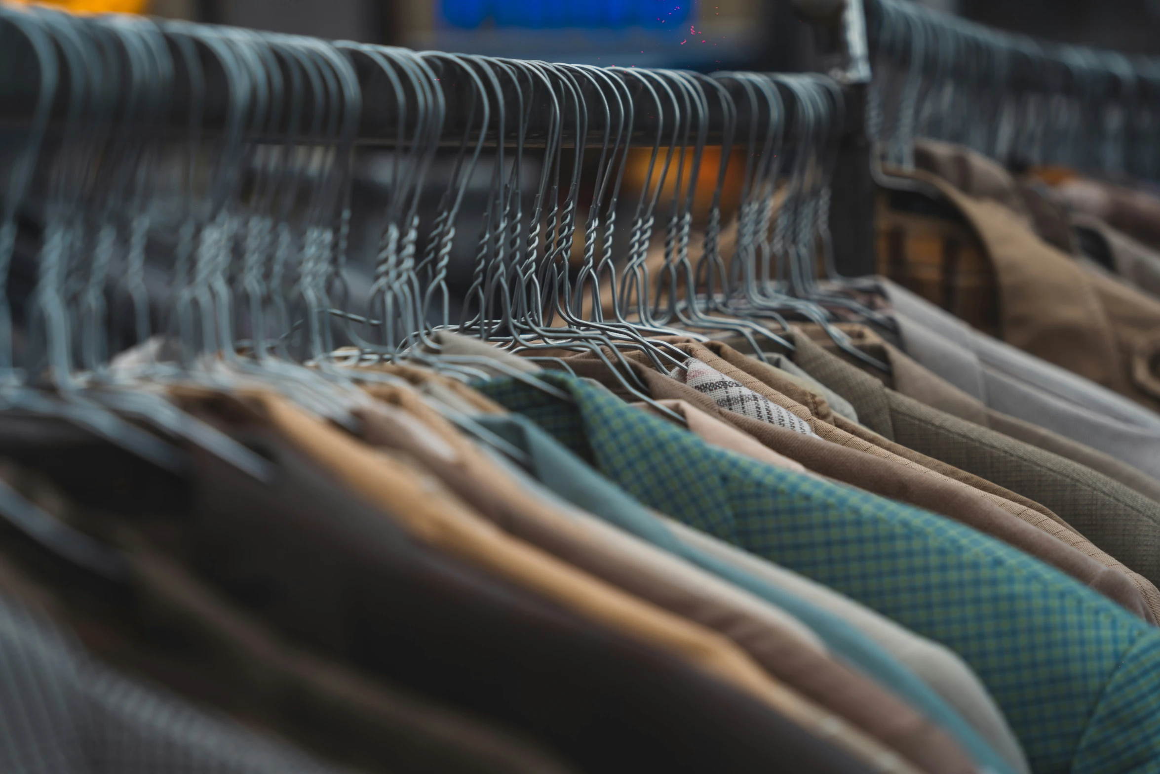 a group of different colored clothing hanging on the rail