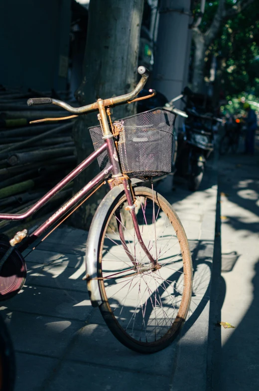 a old bicycle sitting on the sidewalk near a tree