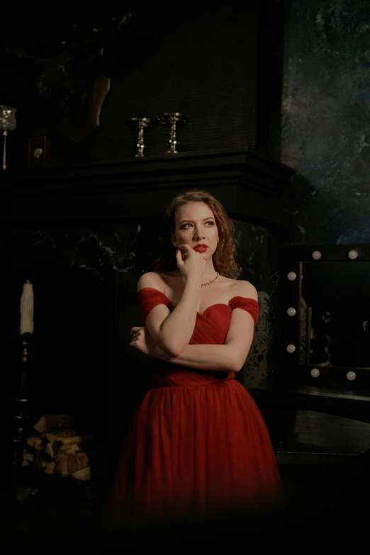 a woman in a red dress is posing in front of a fire place