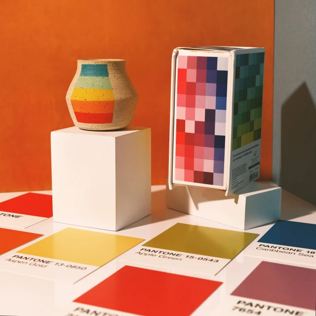 there is a vase and a box with color samples in it