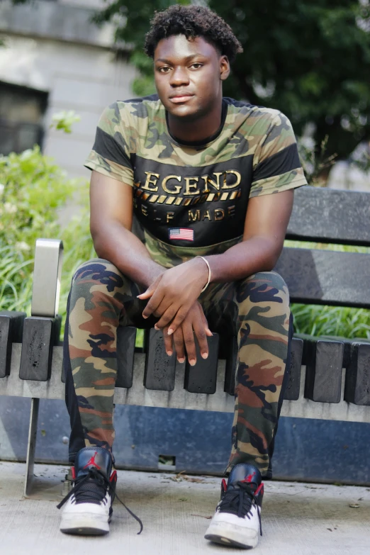 a man wearing camouflage pants sitting on top of a bench