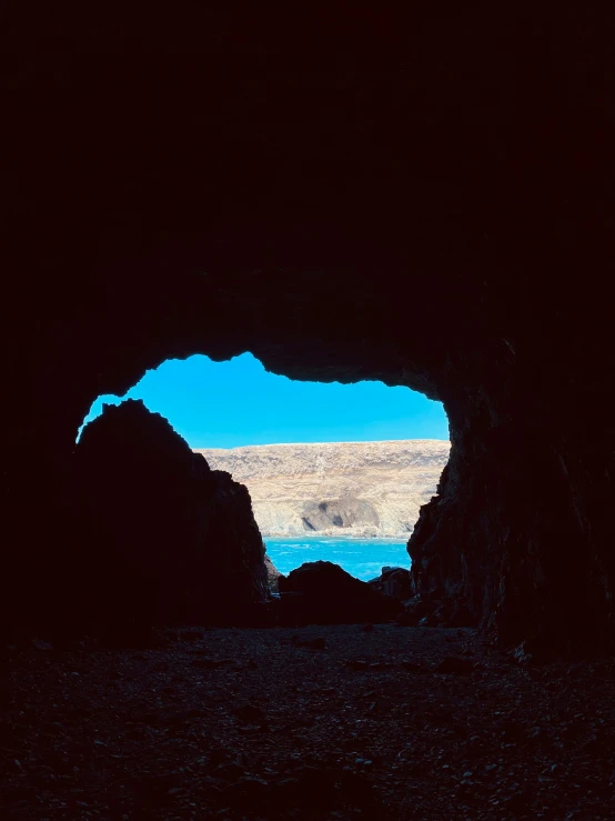 an open cave in the middle of nowhere with sky in the background