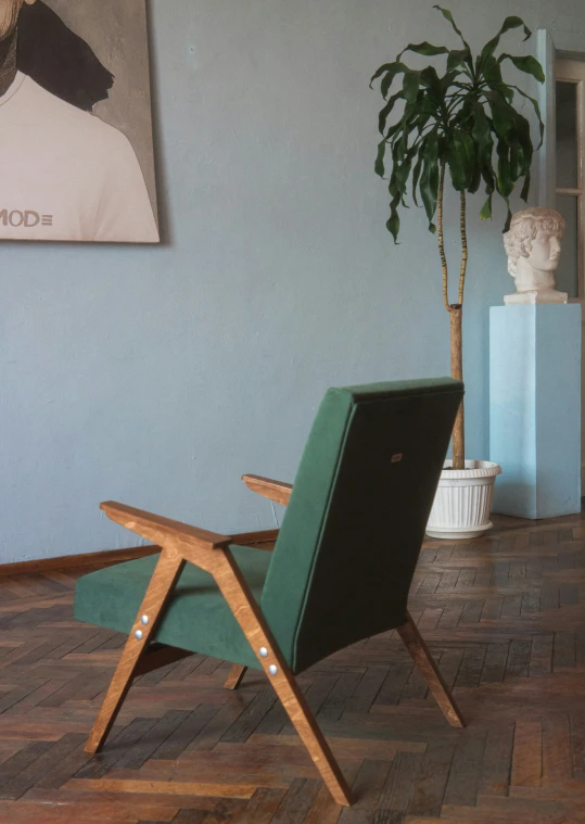 a chair with a plant in it next to a wall with a picture on it