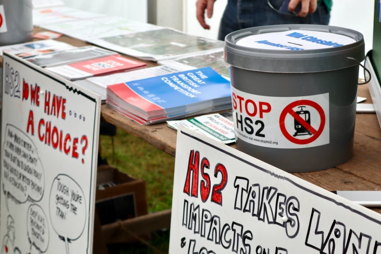 two signs are placed near a metal trash can on a table