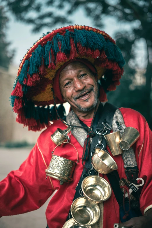 a smiling man with golden bells attached to his neck