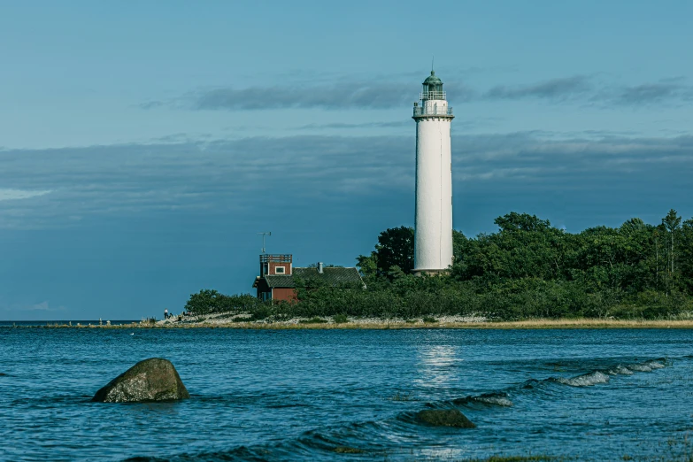 a lighthouse sits on the water next to trees