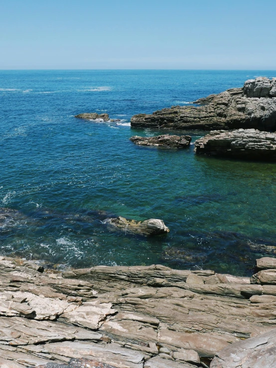 rocky shoreline with blue water on sunny day