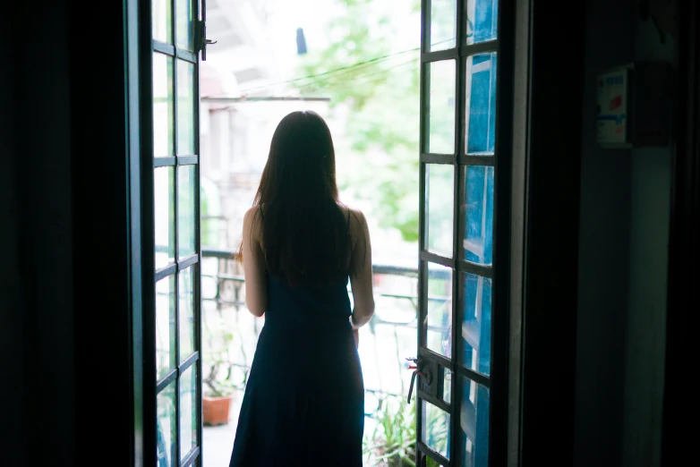 a young woman standing at the open door to an apartment building