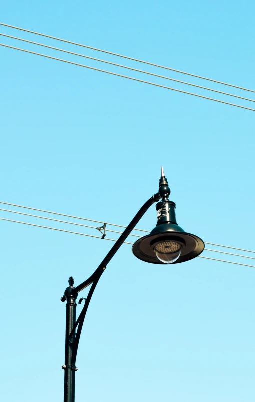 a lamp post sits underneath wires against a blue sky