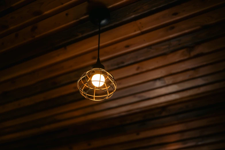 a hanging light with a white bulb in a wooden room