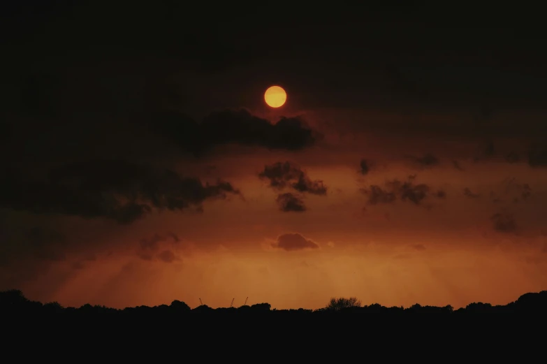 an orange and black sky with a partial moon