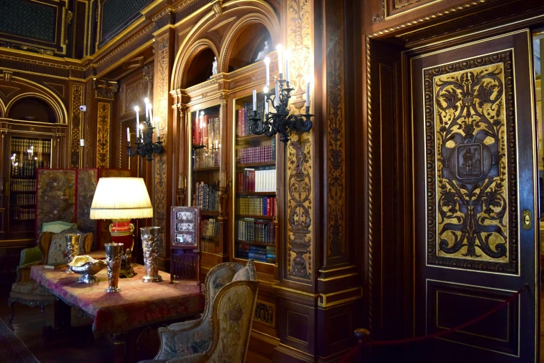the interior of a home liry has a large book shelf with intricate wood carvings on it