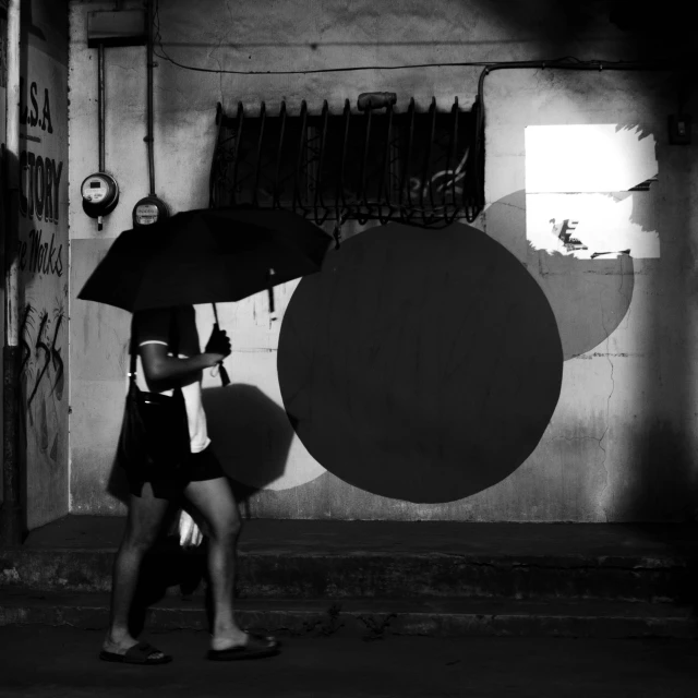 black and white po of a person walking under an umbrella