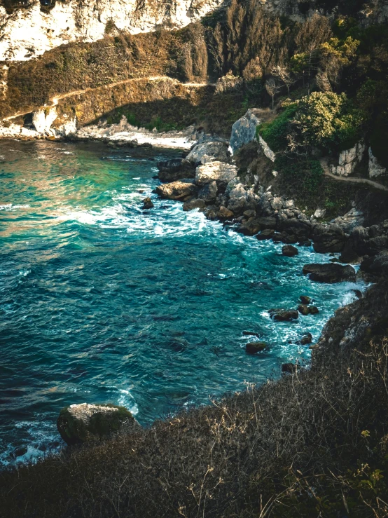 a cliff side overlooking the ocean with a path running through it