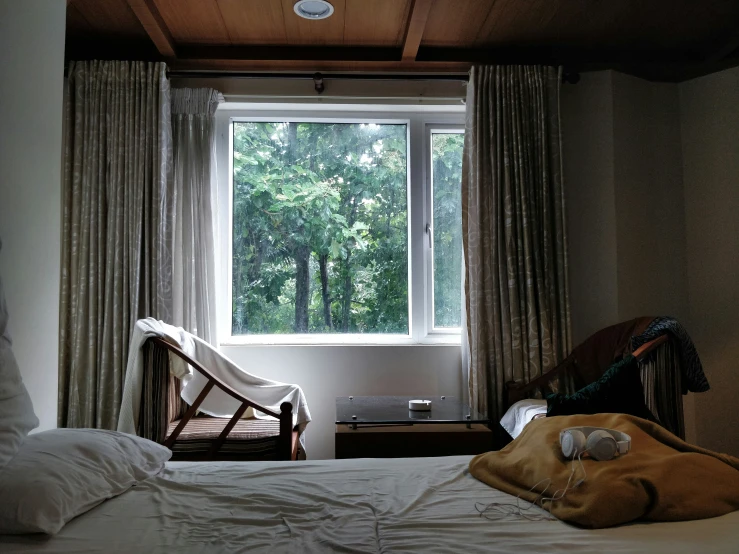 an unmade bed sits in front of a large window with the lights on