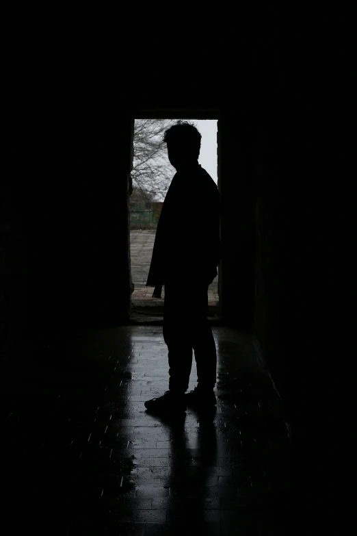 a silhouette of a man standing in the dark in the rain