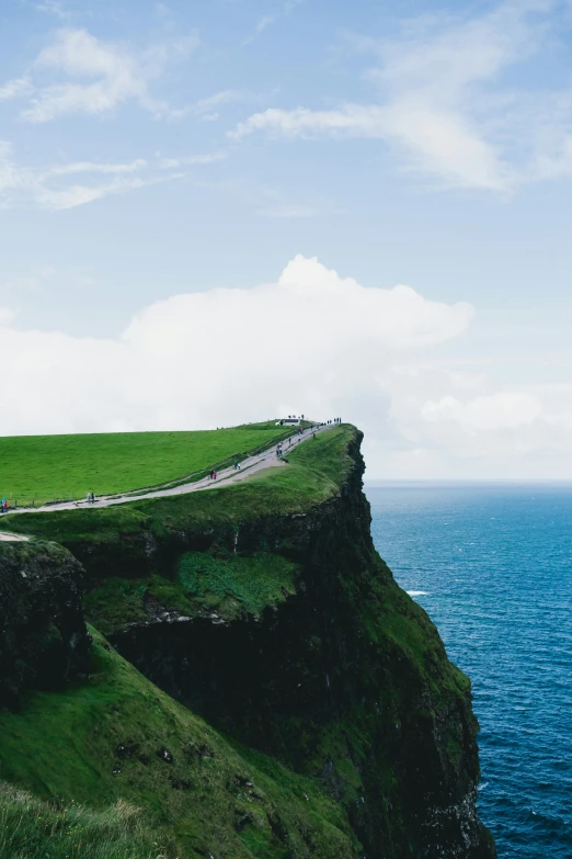 a hill overlooking the ocean with a long road that extends to a cliff