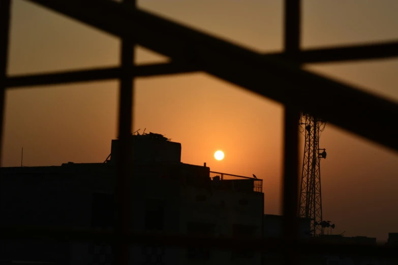 the sun is setting on the horizon with building in the background