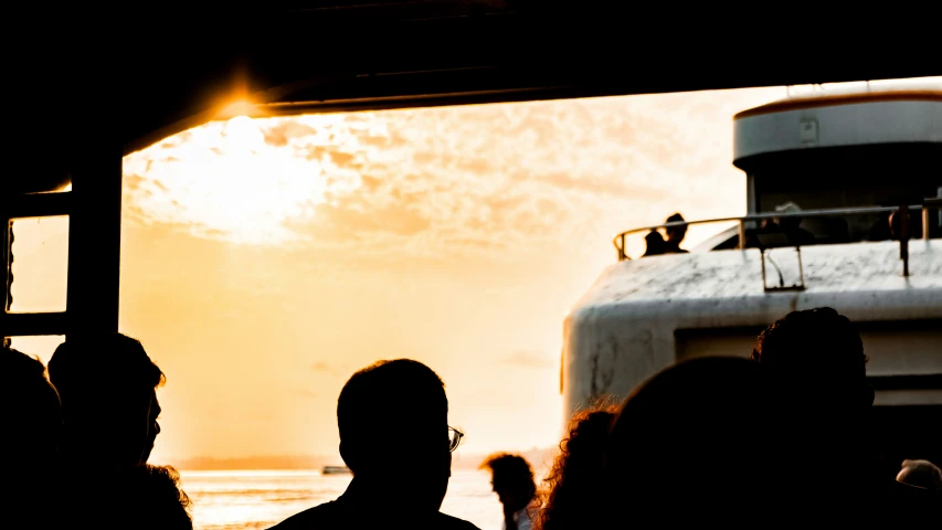 silhouettes of people against an orange sky near a boat