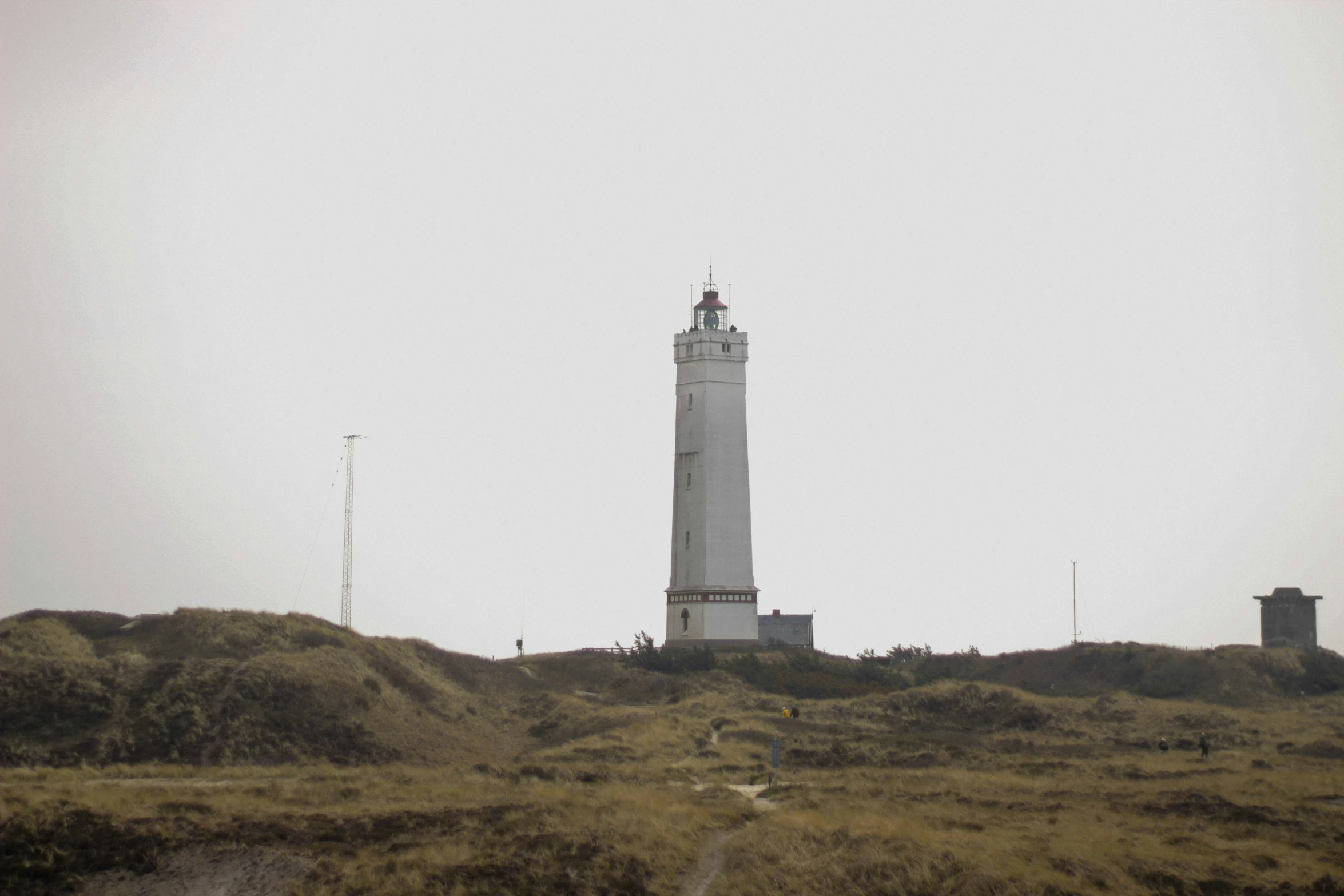 a tower with a small clock is on a hill