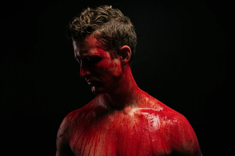 man covered in red body paint posing with his chest open