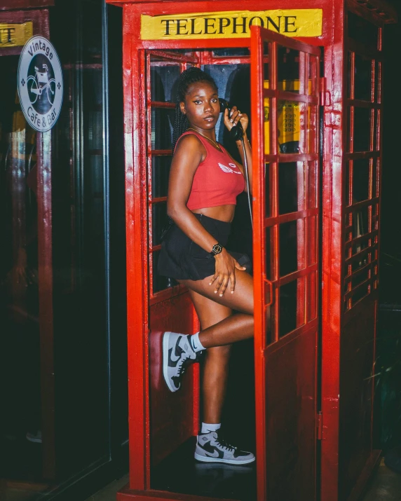 a woman stands in a telephone booth talking on her cell phone