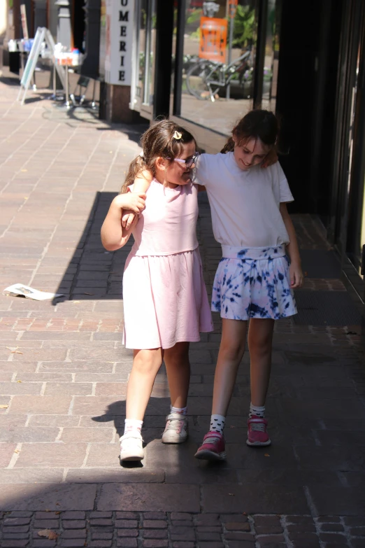 two girls on the sidewalk walking toward soing