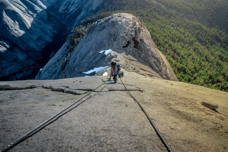 two men walk on a large rock near a mountain