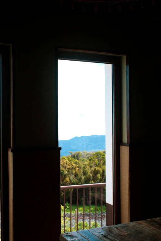 the view from inside an empty room shows mountains, grass and trees
