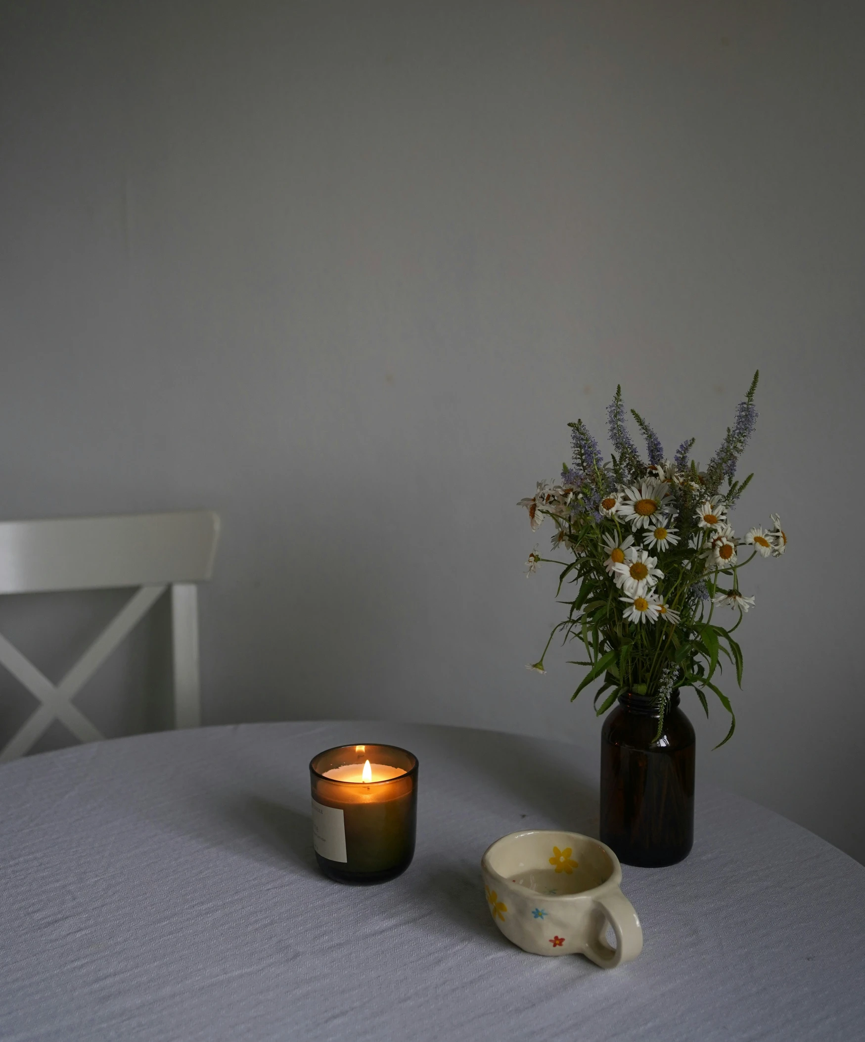 an arrangement of flowers and a candle on a table