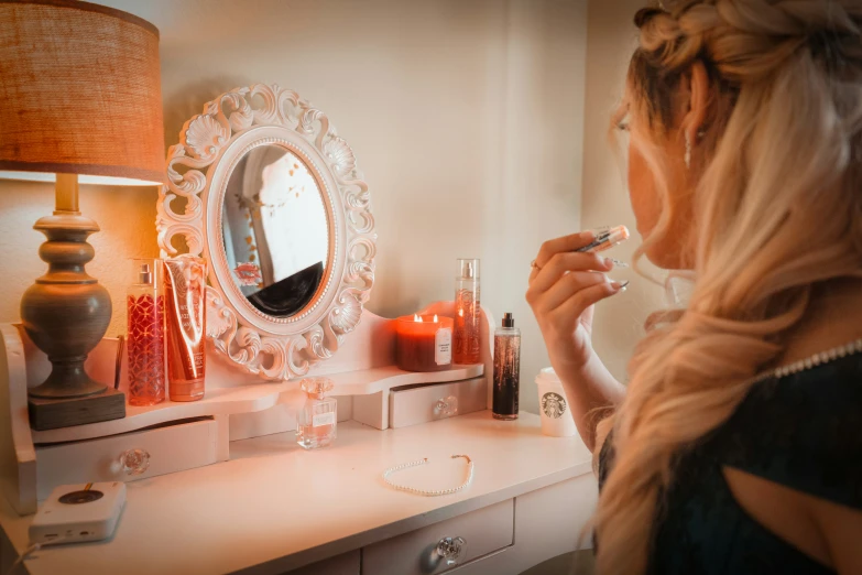 a woman putting on makeup brushes in front of her vanity