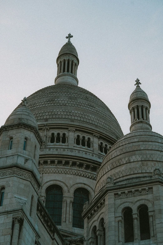 the top of a building with a steeple and cross at the end