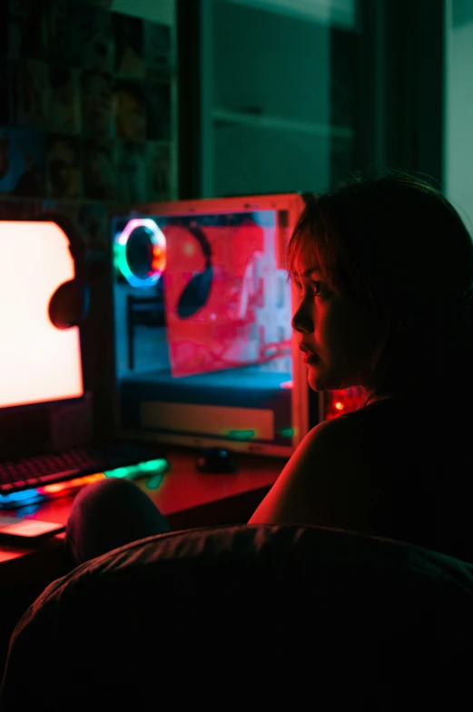 the back of a person's head while he sits at a desk with two computers in front of them