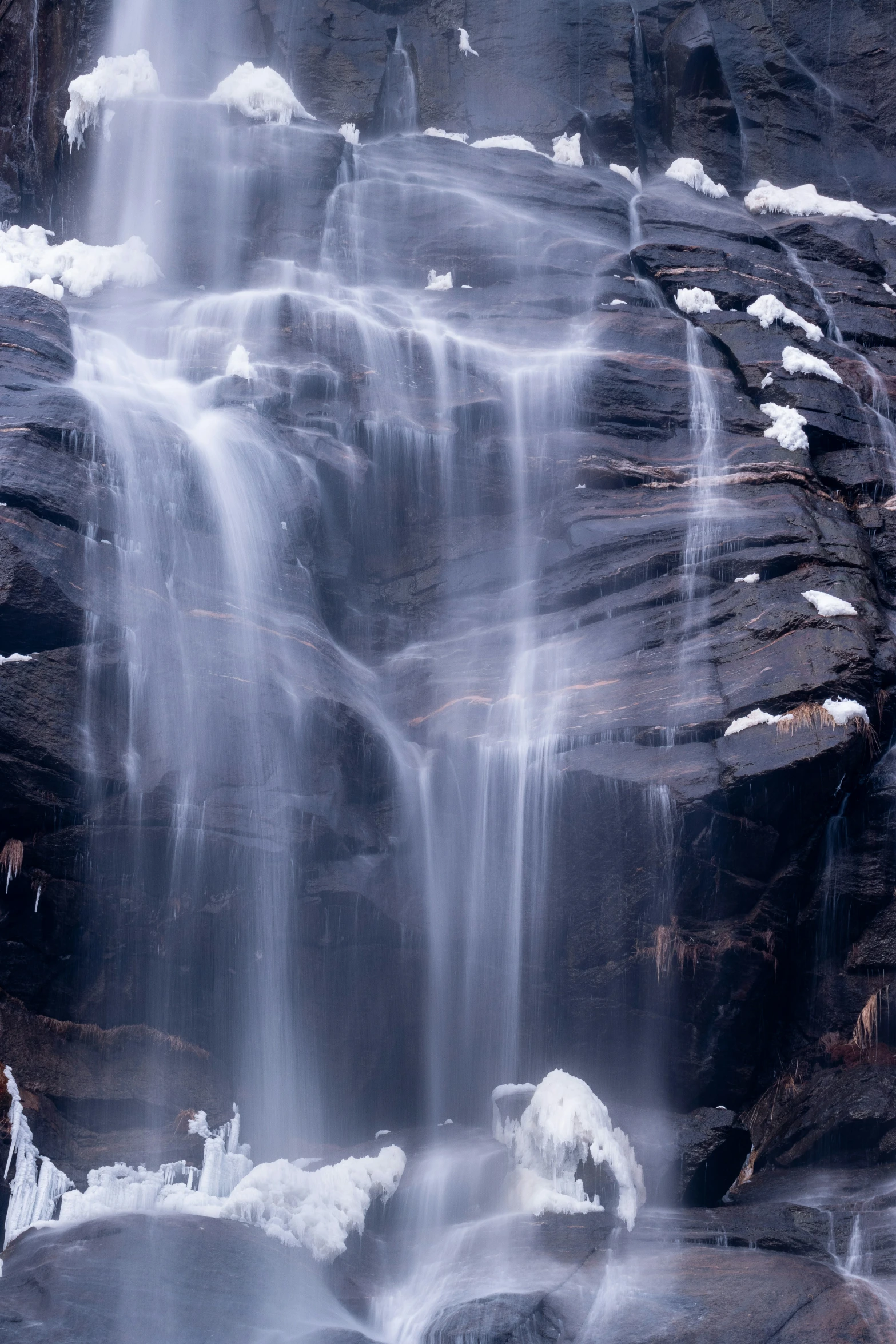 water fall over rocks in a snow covered valley