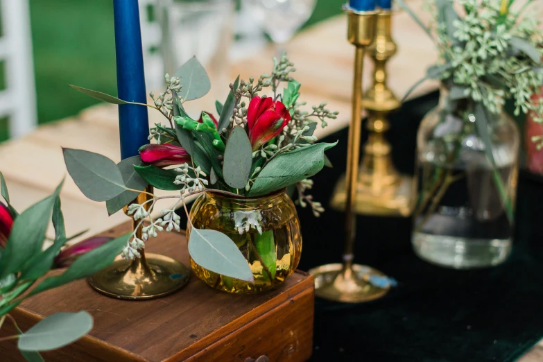 roses, foliage and eucalyptuss sit in vases next to candle holders