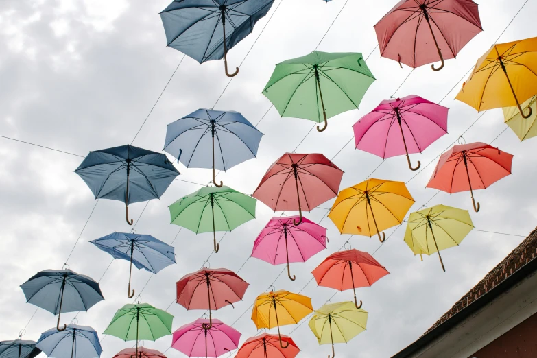 a long line of different colored umbrellas flying in the sky