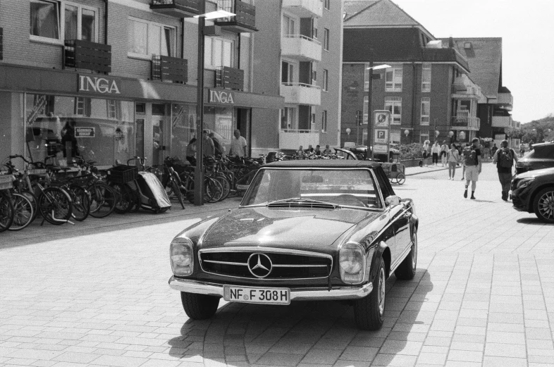 black and white image of old mercedes coupe car on brick pavement