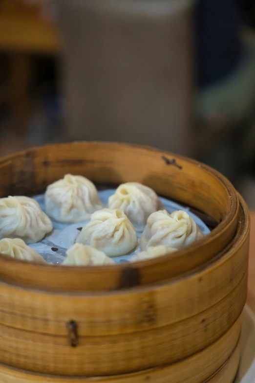 a wooden bowl filled with steamed dumps on top of a white plate